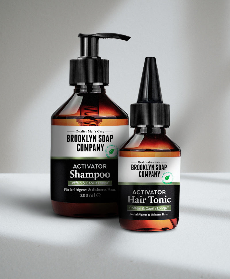 Brooklyn Soap Company Activator Shampoo und Hair Tonic mit Coffein und Capilia Longa® für kräftigeres, dichteres Haar – in braunen Flaschen mit schwarzem Etikett auf hellem Hintergrund.