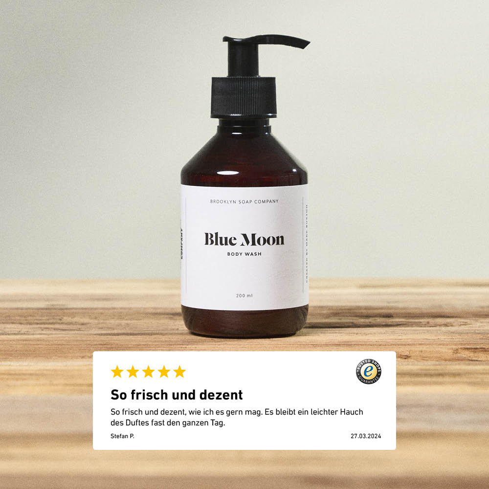 Blue Moon Body Wash 200 ml von Brooklyn Soap Company auf Holztisch, darunter eine Kundenbewertung mit 5 Sternen und dem Kommentar „So frisch und dezent“.