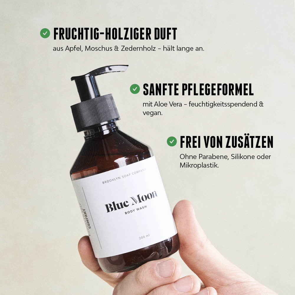 Hand hält eine Flasche Blue Moon Body Wash, daneben Vorteile des Produkts wie fruchtig-holziger Duft, sanfte Pflegeformel und Freiheit von Zusätzen.