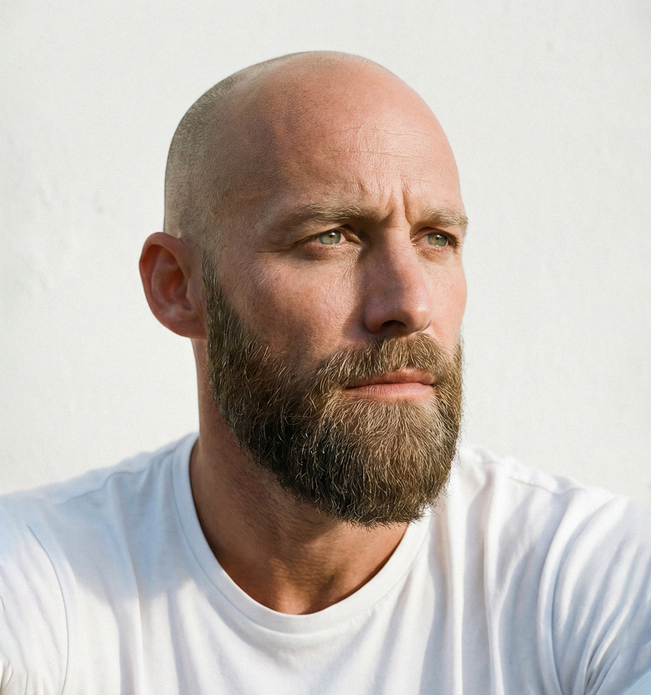 Glatzköpfiger Mann mit Bart blickt nachdenklich zur Seite